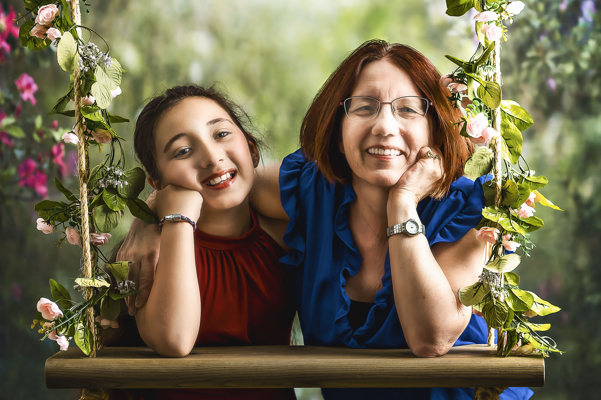 Fine art portrait of young girl in red dress and grandmother in blue blouse relaxed and smiling flower background in studio by Vaudreuil-Soulanges and West Island of Montreal photographer Tobi Malette